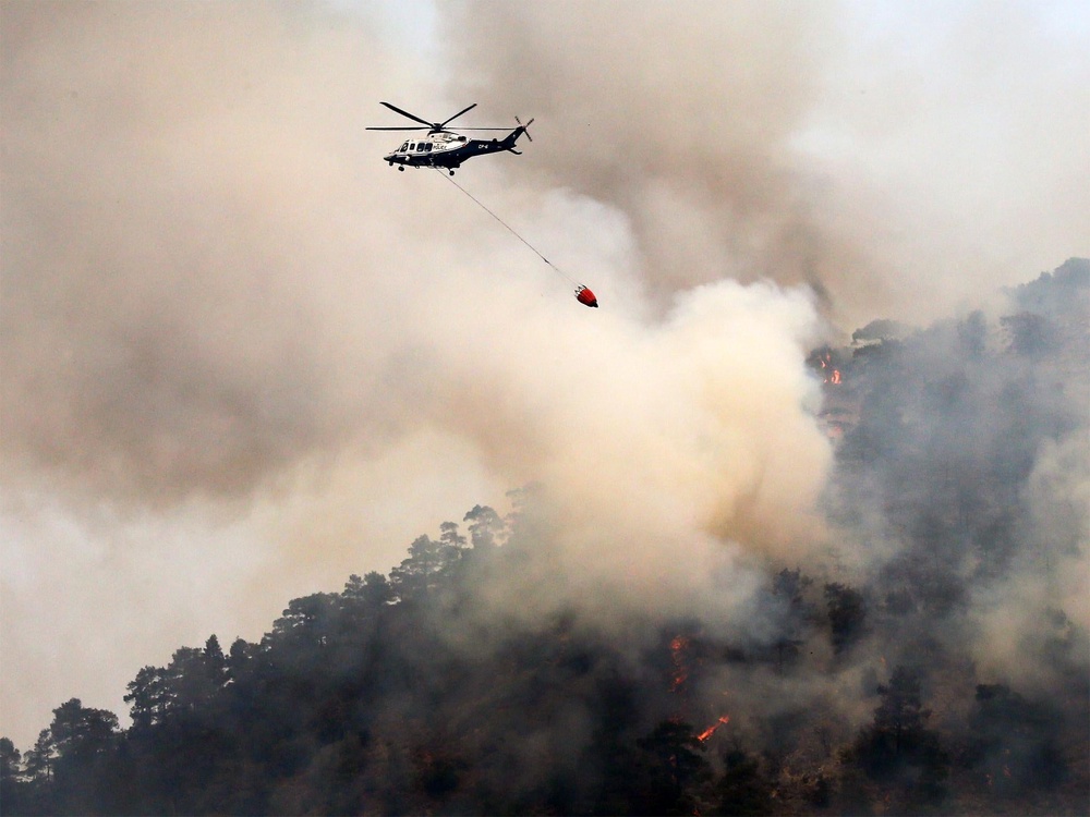 A helicopter drops water on the Troodos mountain area near Nicosia (EPA)