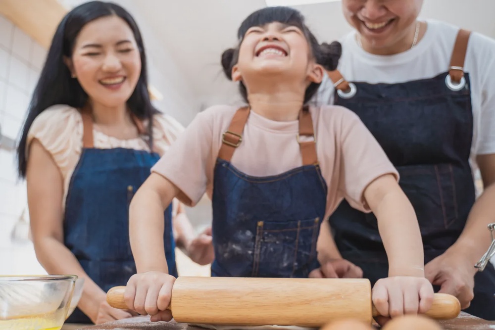 Children involved in cooking activities are often introduced to food preparation through structured, hands-on tasks rather than observation alone.