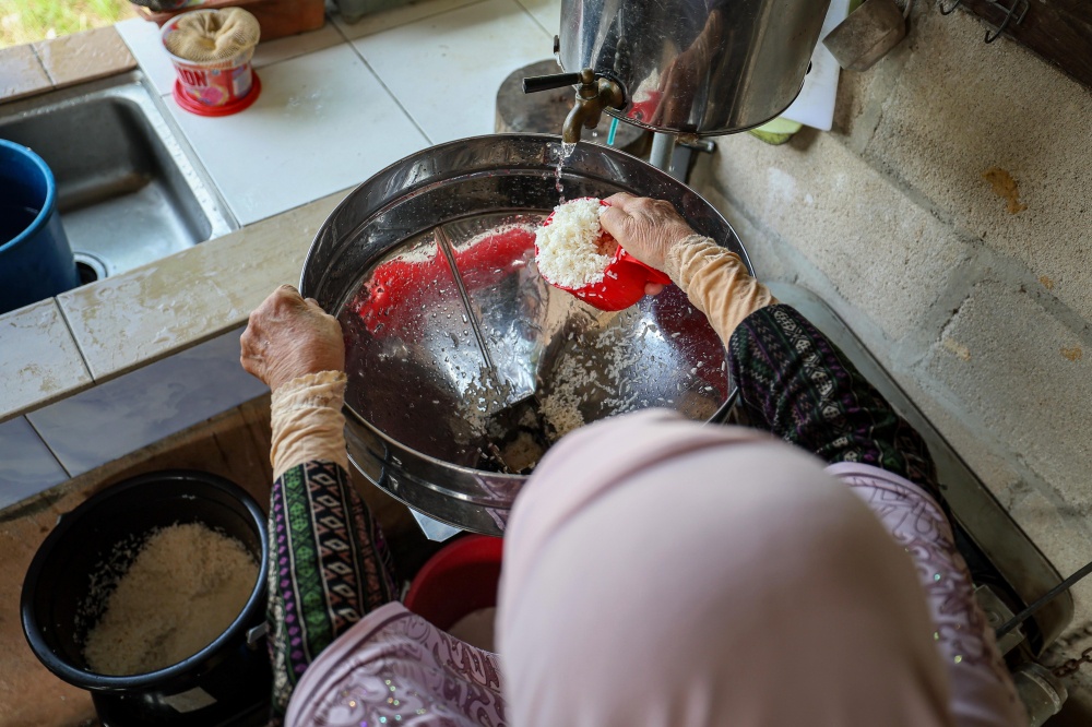 Dodol maker Chik Ah grinds glutinous rice during the dodol-making process at her home in Kampung Jasa, Chemor. — Bernama pic