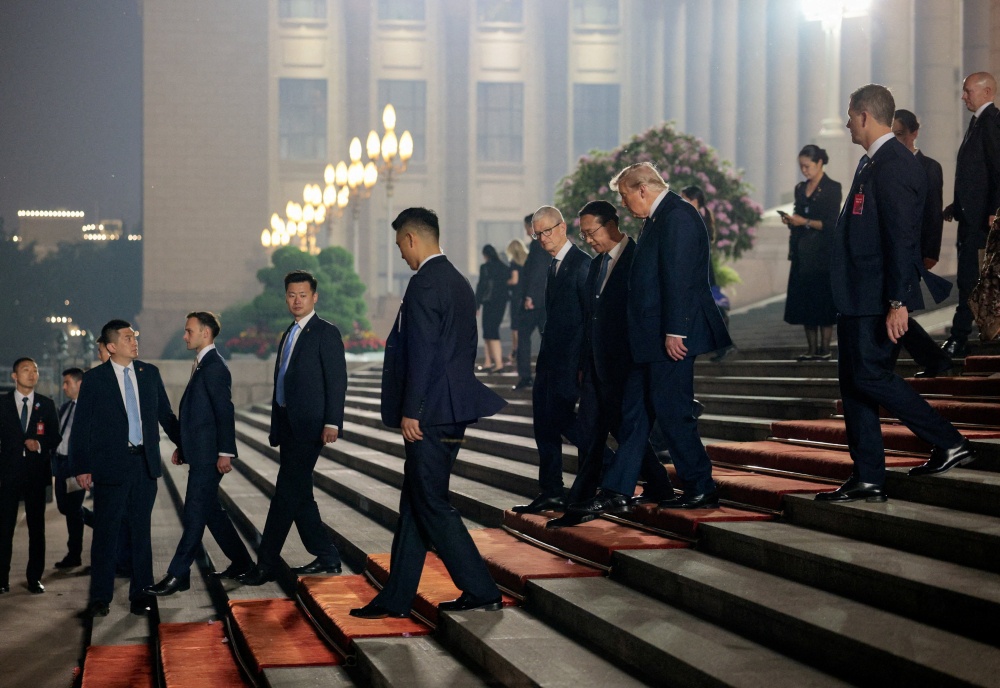 US President Donald Trump, Chinese Vice Foreign Minister Ma Zhaoxu and Apple CEO Tim Cook walk outside the Great Hall of the People after attending a state banquet in Beijing on May 14, 2026. — Reuters pic