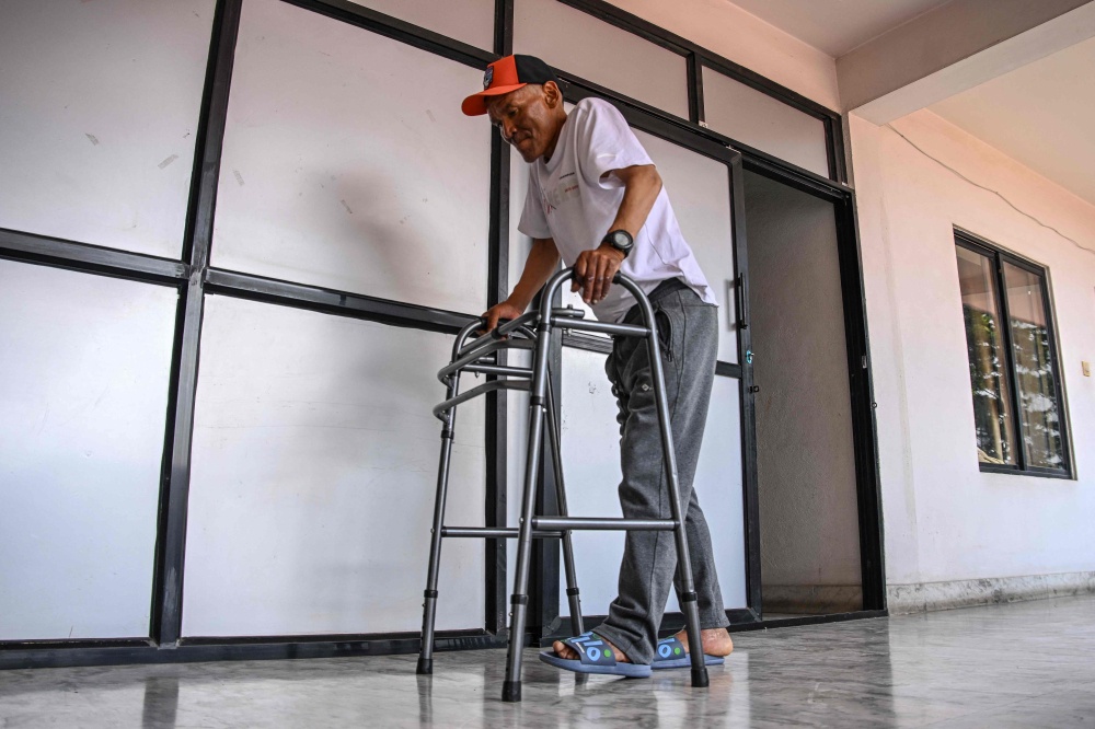 Everest survivor Dawa Sherpa walks with a support during his recovery in Kathmandu June 18, 2026. — AFP pic