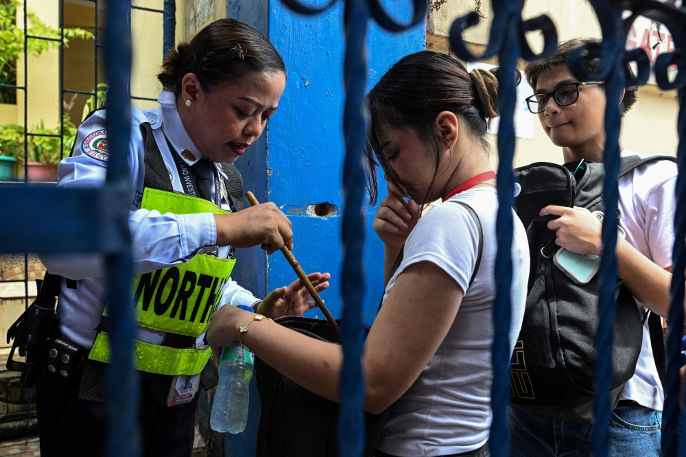A security guard checks the bag of a student entering Batasan Hills National High School in Quezon City, Philippines on June 23, 2026. — Reuters pic