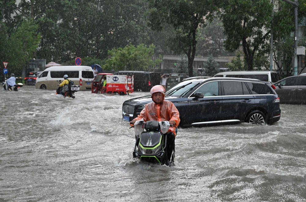 A man on a scooter makes his way along a flooded street in Beijing on July 7, 2026. — AFP pic 