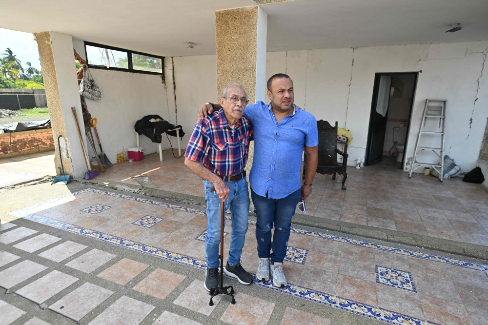 Engineer Elias Chayeb (left) and his son who’s also an engineer and shares his name, Elias Eduardo Chayeb, stand in Catia La Mar, La Guaira state, Venezuela, on July 6, 2026. In a block of flats reduced to ruins by twin earthquakes, a modest three-storey building still stands. — AFP pic