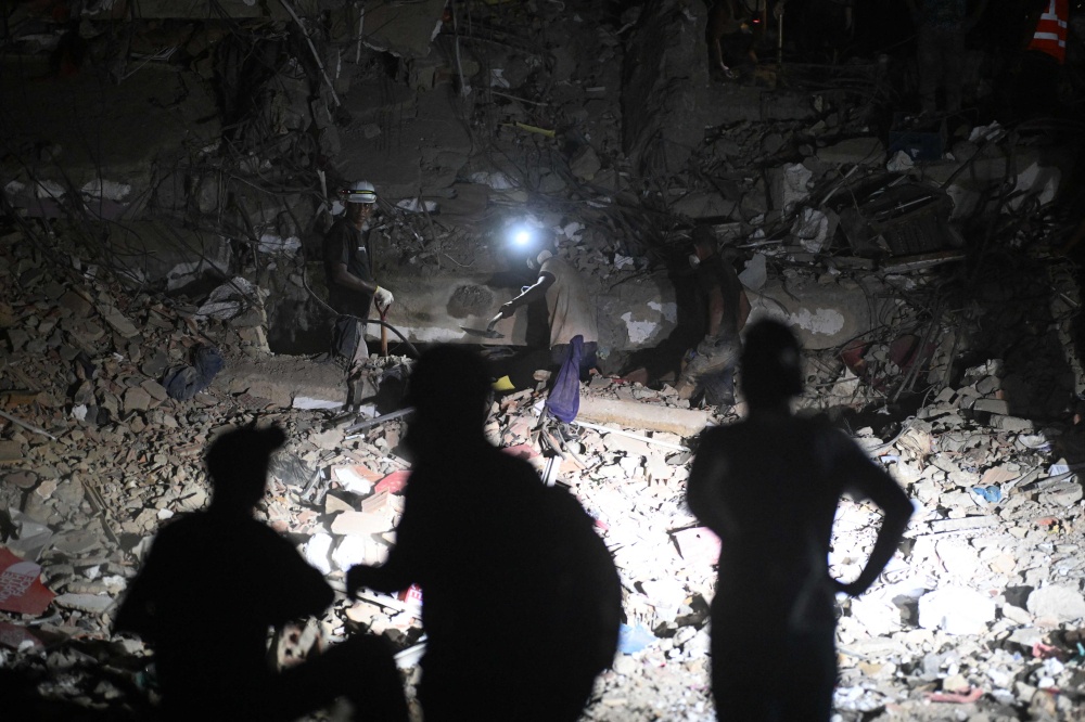 Rescuers and volunteers work with headlamps during nighttime operations on the rubble of a collapsed building in Caraballeda, La Guaira state, Venezuela on July 7, 2026. — AFP pic