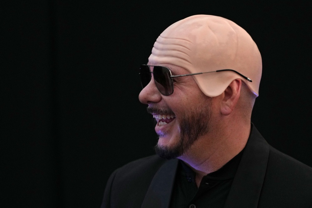 US rapper and singer Pitbull tries on a ‘bald cap’ after receiving a certificate from Guinness World Records for achieving the largest number of people sporting ‘bald caps’ ahead of a concert at BST Hyde Park in London, on July 10, 2026. — AFP pic