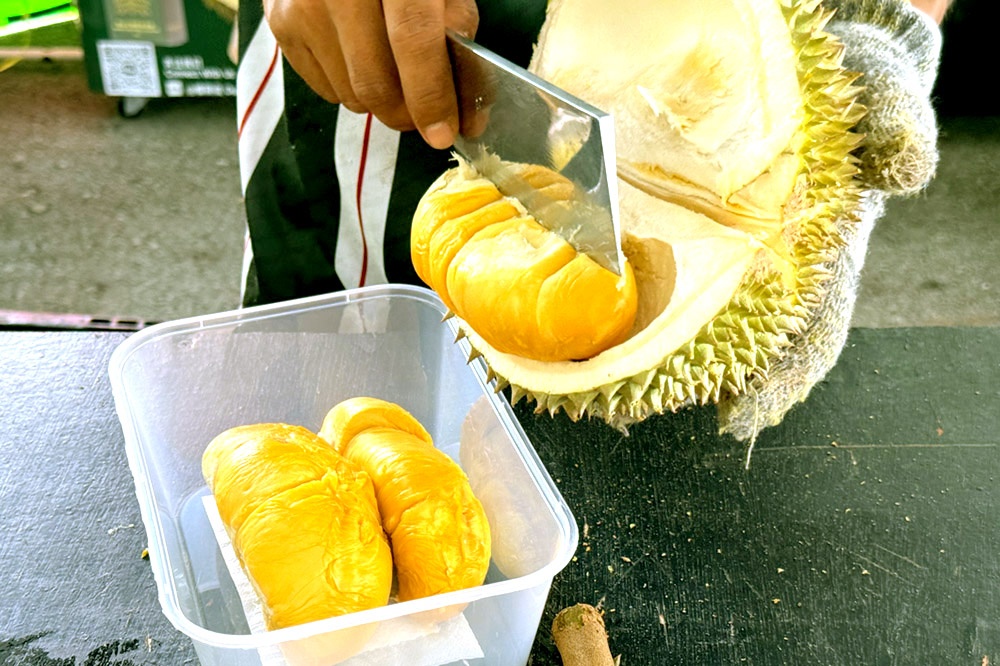 Using a cleaver to break open the King of Fruits. — Picture by CK Lim