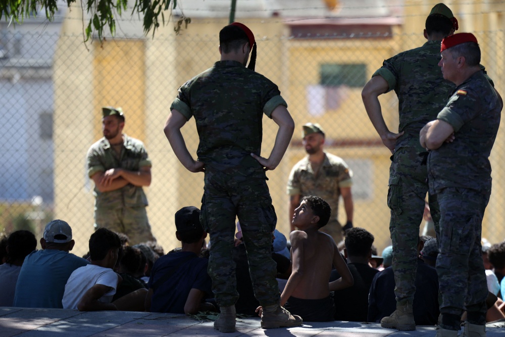 A young migrant looks at a member of the Spanish Army’s ‘Regulares’ infantry force near the border post, prior to escorting them back to Morocco, in the Spanish enclave of Ceuta on August 2, 2026. — AFP pic