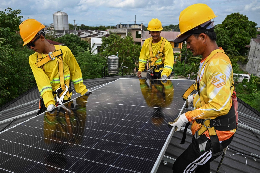Workers install solar panels on a roof in Carmona, Cavite on July 9, 2026. — AFP pic