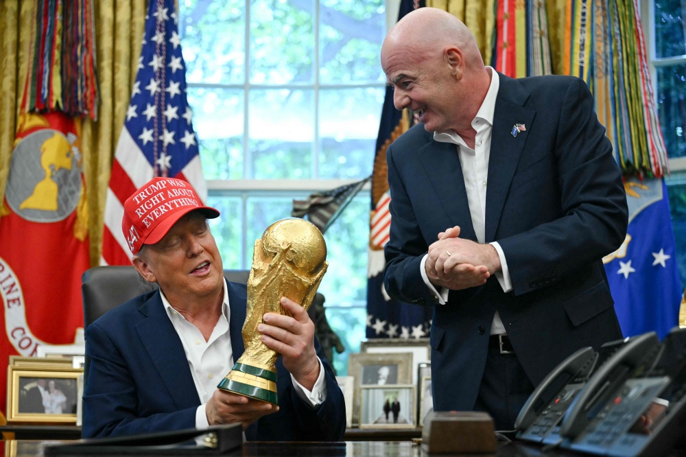 US President Donald Trump holds the World Cup trophy with Fifa chief Gianni Infantino during the 2026 draw announcement at the White House, August 22, 2025. — AFP pic