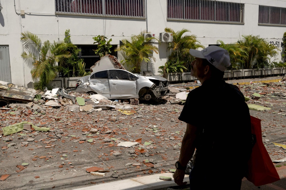 A man stands next to a destroyed car following an earthquake in Pereira, Colombia on August 11, 2026. Colombian volunteers and rescuers cleared rubble with their bare hands to search for survivors early on August 11 after the country's strongest earthquake in a decade killed at least 169 people and smashed dozens of buildings. — AFP pic