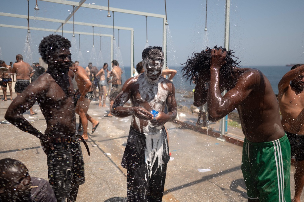 Migrants take a shower after swimming across to the Spanish enclave of Ceuta in North Africa on August 15, 2026. — AFP pic