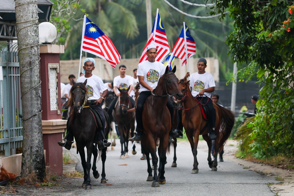 Kampung Seri Pulau residents parade with Jalur Gemilang on horseback during Maulidur Rasul and National Month celebrations in Kubang Kerian. — Bernama pic