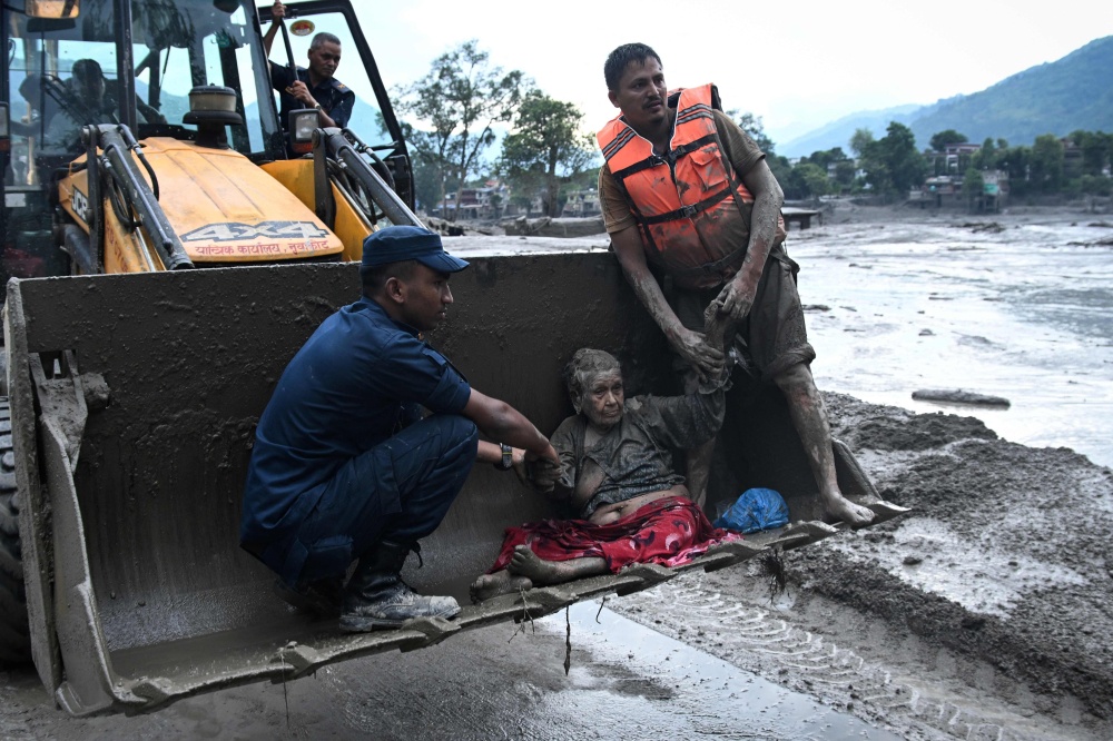 Rescuers use an excavator to transport a flood survivor following flash floods and a landslide in Devghat, Nepal’s Nuwakot district, on August 26, 2026. — AFP pic