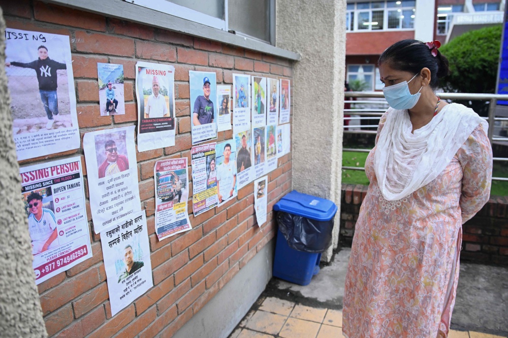 A woman looks at photographs of people missing after flash floods in Nepal outside a hospital in Kathmandu on August 29, 2026, as families, including those of nine missing Singaporeans, wait anxiously for news of their loved ones. — AFP pic