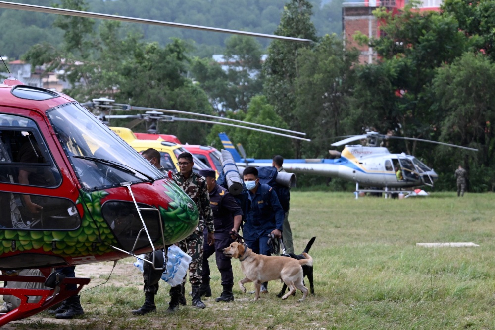 Security personnel with sniffer dogs board a helicopter bound for the flood-affected Mailung valley from Trishuli camp in Nepal’s Nuwakot district on August 29, 2026.  — AFP pic