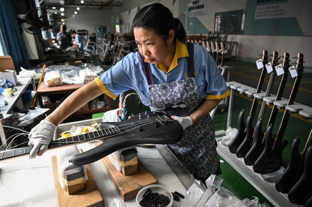 This photo taken on July 27, 2026 shows an employee working on a guitar production line at a factory of Shenqu musical instrument manufacturer in Zheng’an, in south-western China’s Guizhou Province. — AFP pic 