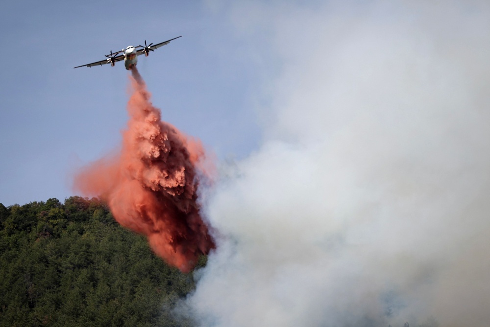 This photograph shows a Bombardier Dash 8 Q400 MR aircraft dropping fire retardant over a forest fire  near Puilaurens, south-western France September 5, 2026. — AFP pic