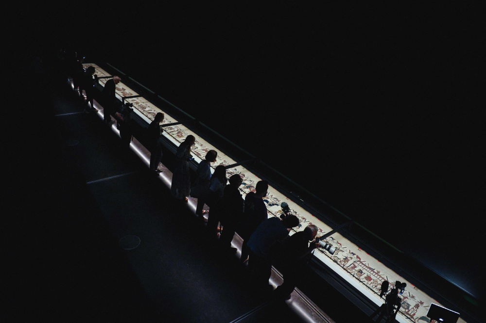 People lean over the display case to take a closer look at the Bayeux Tapestry during a media preview ahead of the official opening at the British Museum in central London on September 7, 2026. — AFP pic
