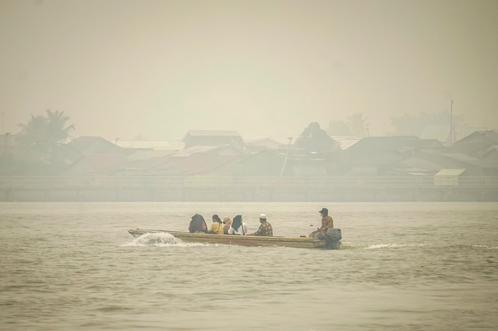 Indonesian villagers travel by boat through thick haze blanketing Benua Melayu Darat, West Kalimantan, as forest fires continue to choke Borneo, Sumatra and South-east Asian neighbours Malaysia and Singapore in September 2026. — AFP pic