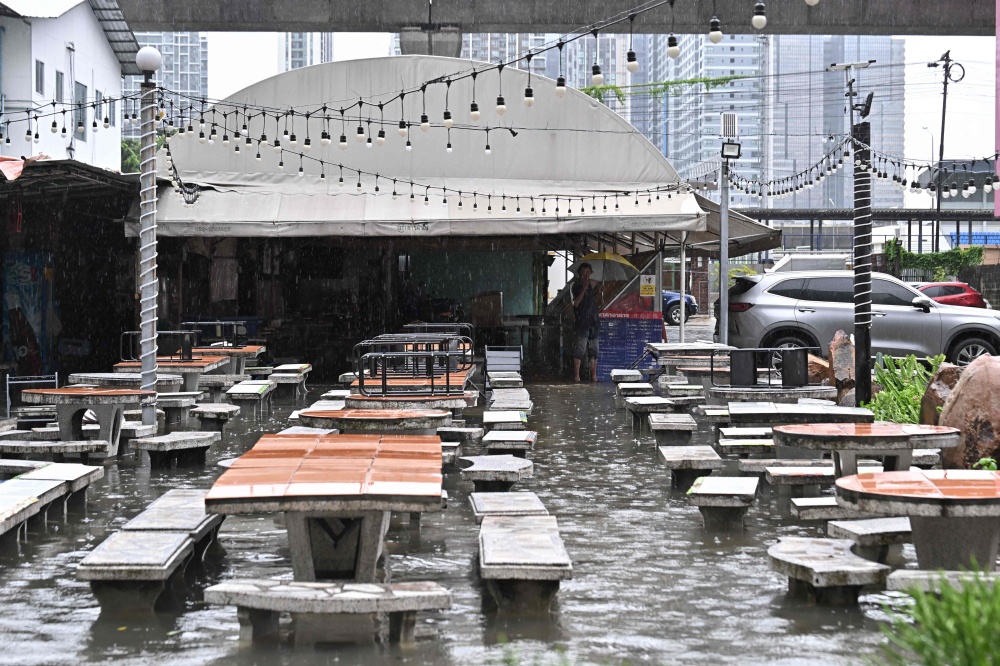 A man looks out from a flooded restaurant in Bangkok on September 26, 2026. — AFP pic