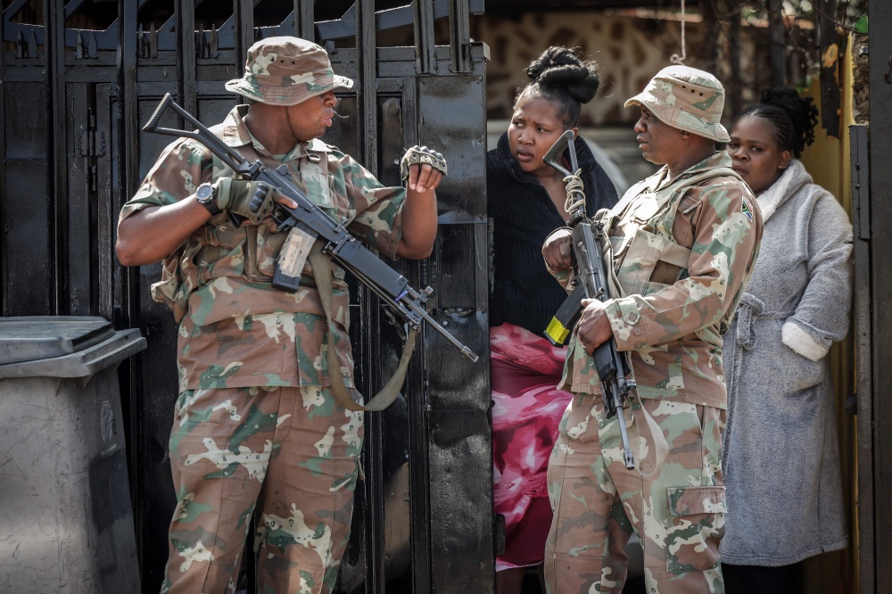 Members of the South African National Defence Force (SANDF) speak with residents near the scene where gunmen armed with assault rifles stormed a bar in Johannesburg on September 27, 2026. — AFP pic