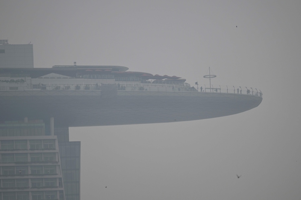 People stand on the observation deck of the Marina Bay Sands on a hazy day in Singapore September 28, 2026. — AFP pic
