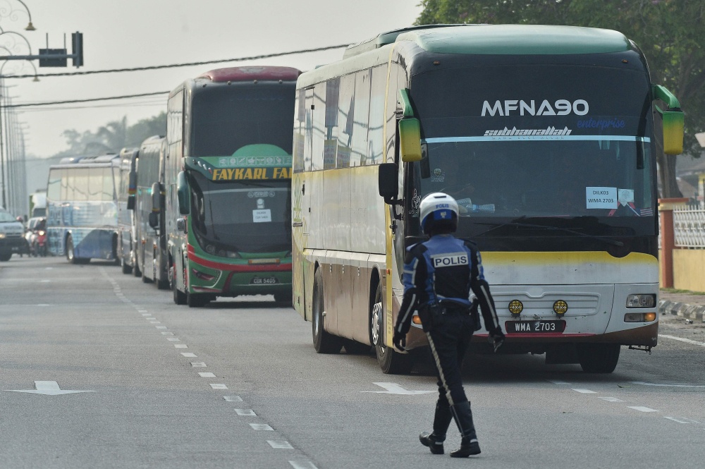 A policeman walks in front of buses carrying Myanmar nationals being repatriated from Malaysia to their homeland, seen heading toward the naval base in Lumut, on the outskirts of Kuala Lumpur September 29, 2026. — AFP pic