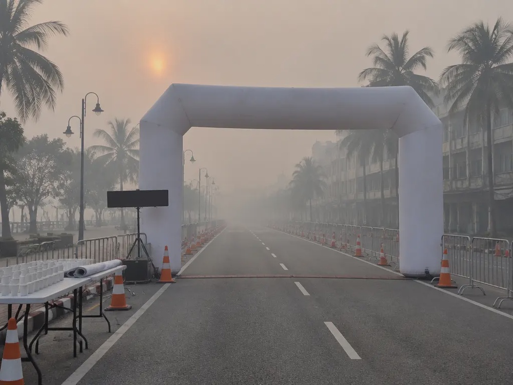烟霾笼罩的清晨，古晋马拉松起点空无一人，白色拱门与路障静静立在封路的街道上