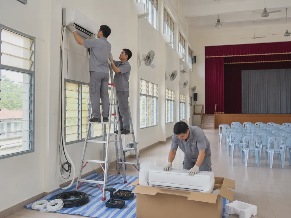 学校礼堂内工人正在安装壁挂式冷气机，改善礼堂环境