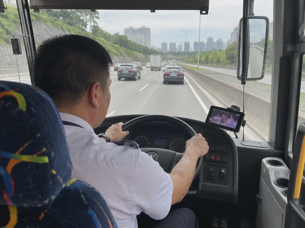 示意图:长巴司机驾驶时,右侧放着一部亮着屏幕的手机。