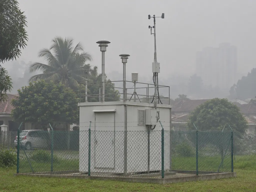 烟霾中的户外空气质量监测站，屋顶设有采样管和气象杆（示意图）