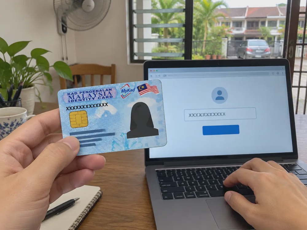 手持MyKad在电脑上输入身份证号码查询援助金资格的示意画面