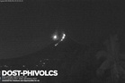 Moment meteor flies through sky beside erupting volcano