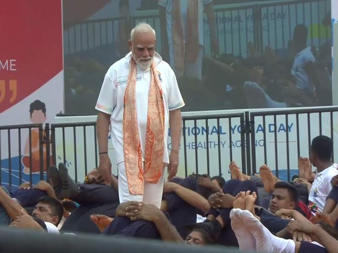 Image from: PM Modi helps participants correct their posture as they perform yoga at IDY celebrations in Kolkata