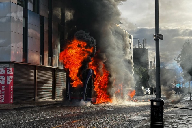 Belfast stabbing latest: Protesters set bus on fire as man charged with attempted murder after knife attack