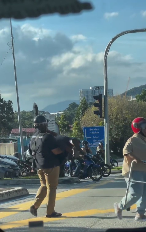 Image from: Kind motorcyclist carries elderly woman across busy road in Taman Melawati